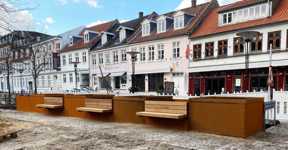 områdefornyelse af Mathilde Fibgers Have i Aarhus med By Bangs plantekummer i cortenstål med bænke monteret på sider, som er beklædt med mahogni planker