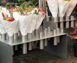 bord i rustfrit stål med mange holdere til krukker med blomsterstilke i butikken i København