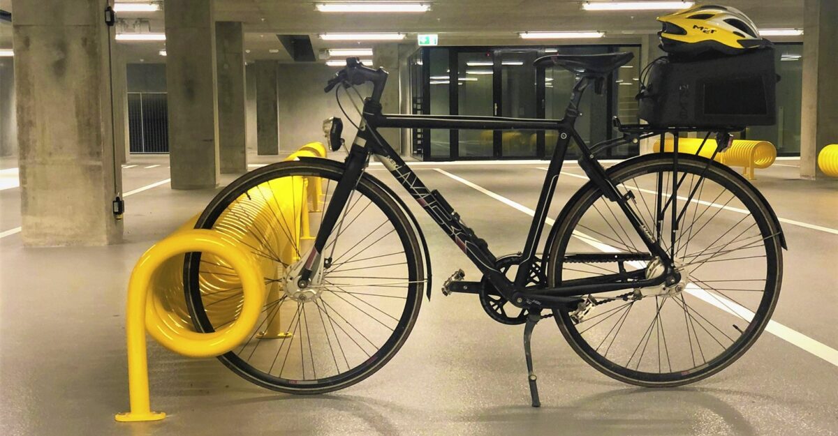 Omega spiralformet cykelstativ i galvaniseret stål og malet i gul til parkering af mange cykler fra begge sider