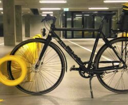 Omega spiralformet cykelstativ i galvaniseret stål og malet i gul til parkering af mange cykler fra begge sider