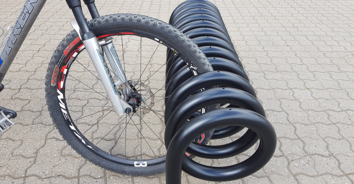 Omega spiralformet cykelstativ i galvaniseret stål og malet i sort til parkering af mange cykler fra begge sider