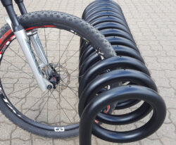 Omega spiralformet cykelstativ i galvaniseret stål og malet i sort til parkering af mange cykler fra begge sider