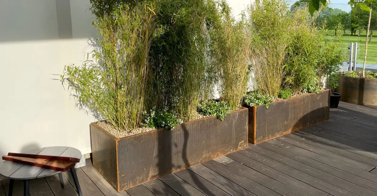 Smukke plantekummer og plantekasser i cortenstål står i en privat have
