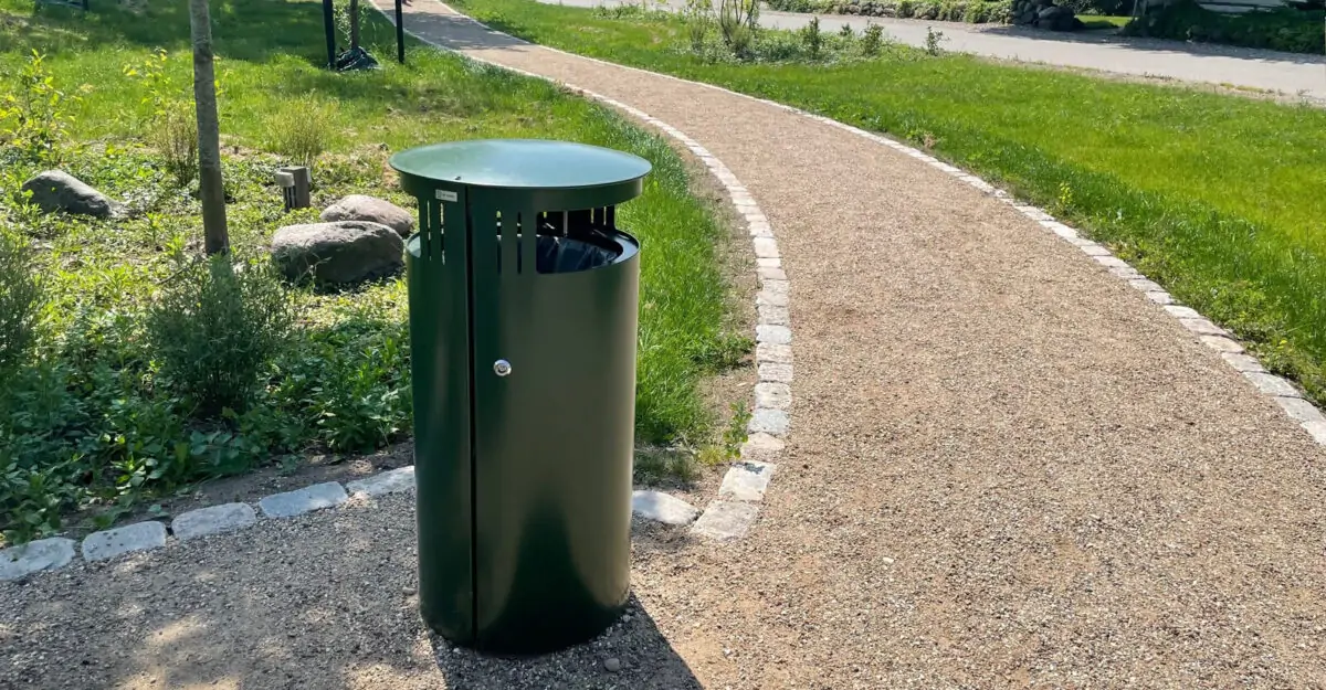 en udendørs affaldsbeholder med dobbelt sideindkast fremstillet i malet galvaniseret stål står i parken i Nørre Søby