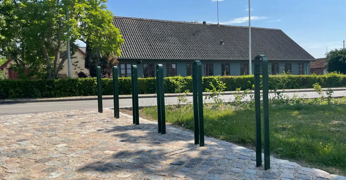 en række cykelparkerings steler fremstillet i malet galvaniseret stål står i parken i Nørre Søby