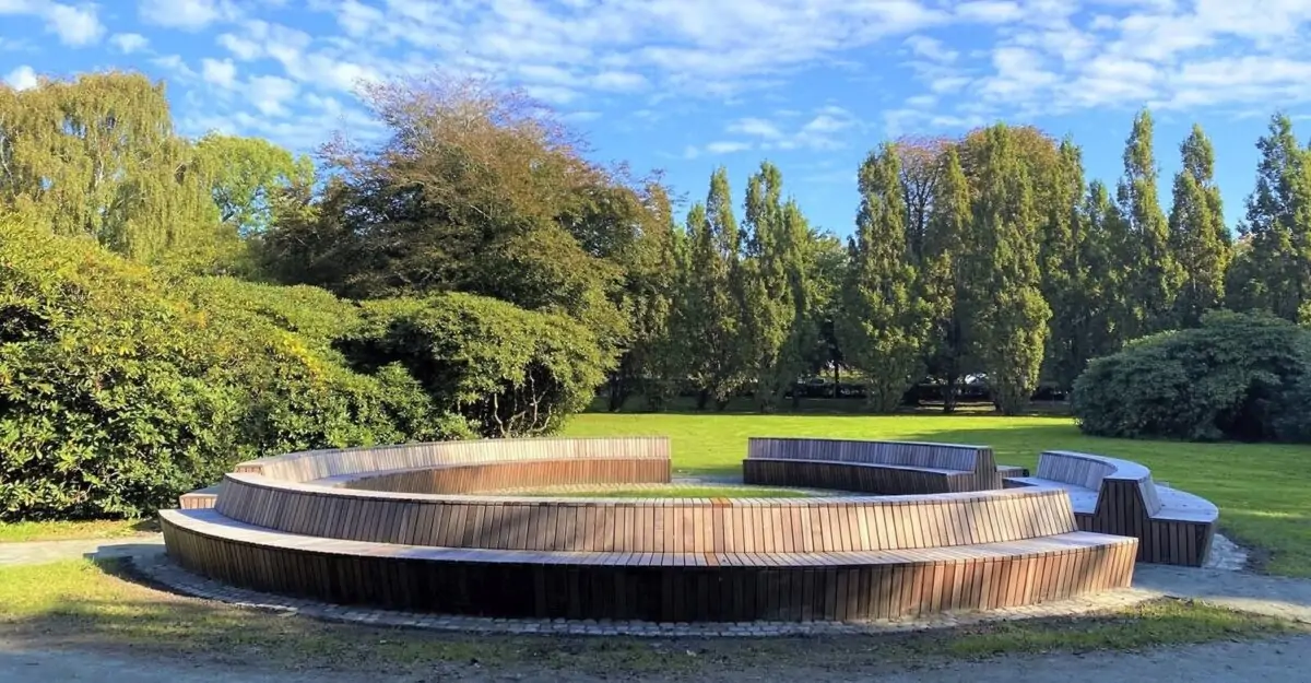 en stor modulopbygget cirkelbænk i galvaniseret stål og beklædt med mahogni stave i parken ved Tønder Gymnasium