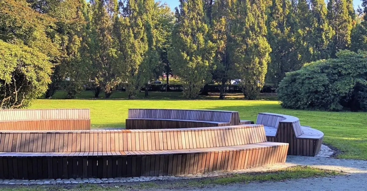 en stor modulopbygget cirkelbænk i galvaniseret stål og beklædt med mahogni stave i parken ved Tønder Gymnasium