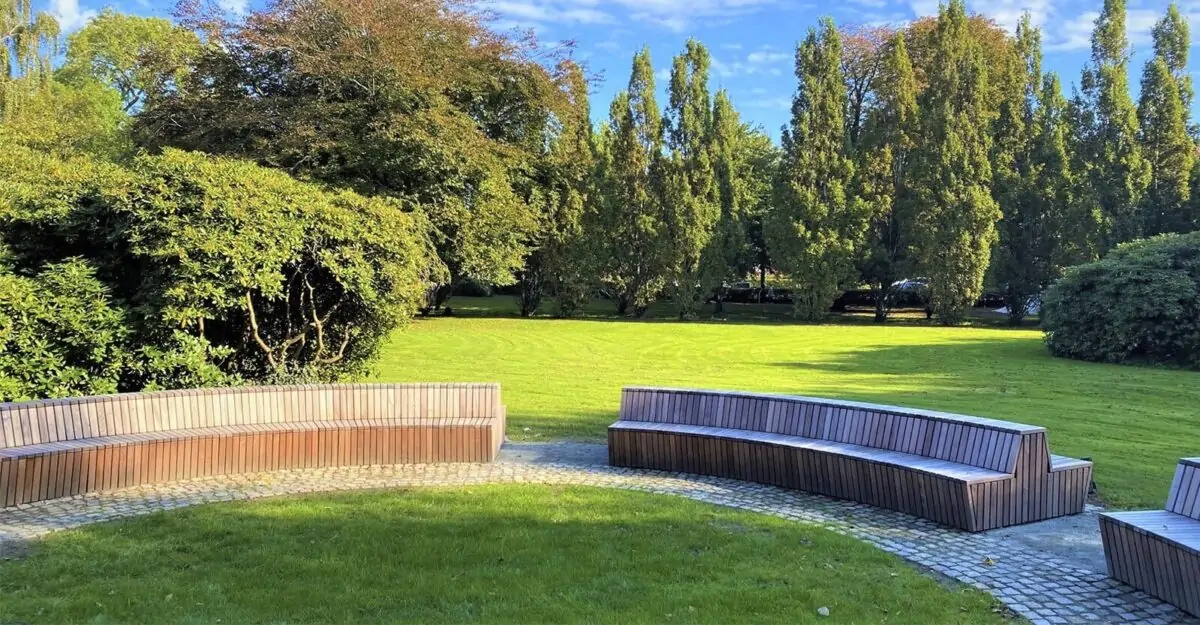 en stor modulopbygget cirkelbænk i galvaniseret stål og beklædt med mahogni stave i parken ved Tønder Gymnasium