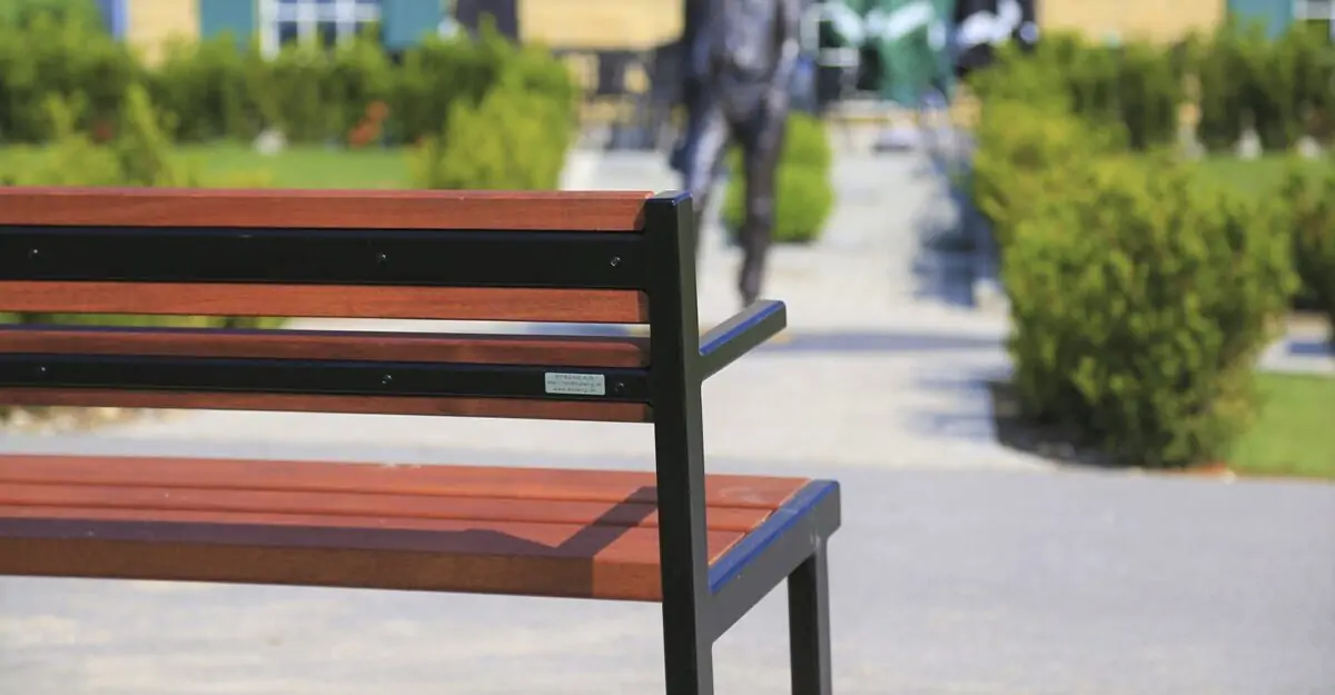 Crepa - en enkel bænk med armlæn til park og byrum fremstillet af malet galvaniseret stål og beklædt med træ