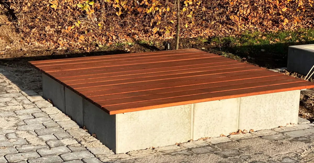 en betonkasse ved legepladsen beklædt med lakeret mahogni planker som en plint